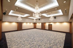 Una vasta sala conferenze con tappeto a motivi, pareti in pannelli di legno e un lampadario centrale.