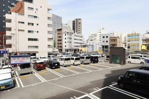 A parking lot with multiple vehicles, including cars and vans, and a small building in the foreground. - HOTEL MYSTAYS Kumamoto Riverside (Kumamoto City)