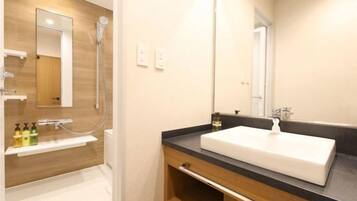A modern bathroom with a wooden vanity, a white sink, and a large mirror.