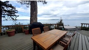 A wooden deck with a table and chairs, overlooking a body of water.