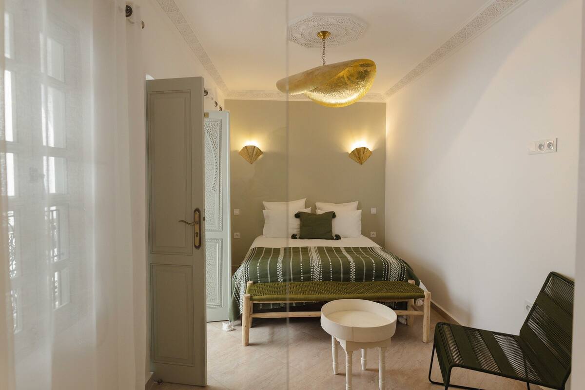 A bedroom with a bed, bedside tables, a bench, and a ceiling light fixture.