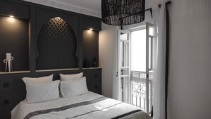 Un dormitorio con cama, pared estampada, lámpara colgante y vistas al exterior.