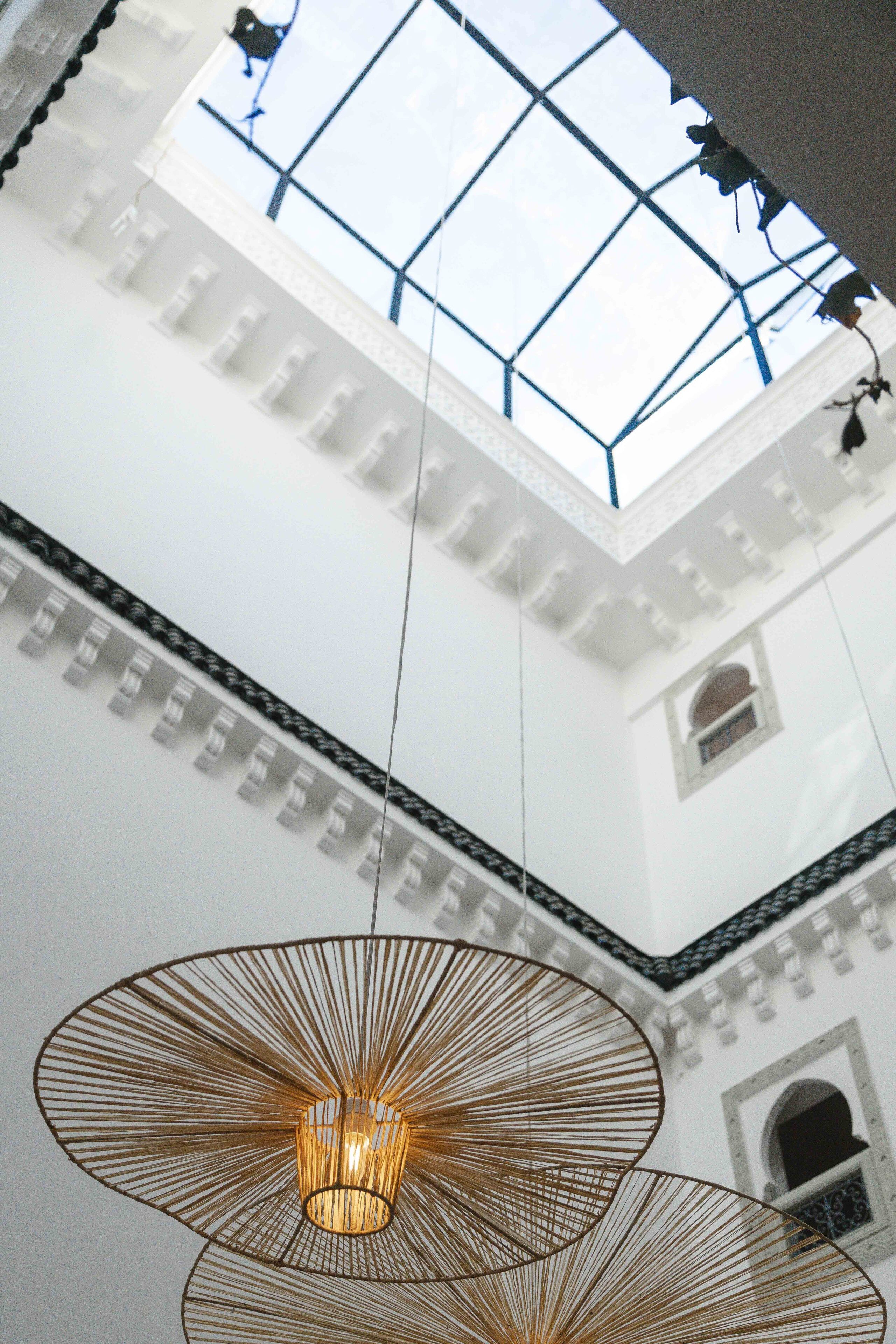 Un plafond haut avec une lucarne et des lampes suspendues.