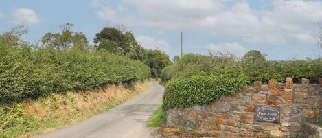 A rural road with a stone wall and a sign indicating 'Lon Profat Fran Goch Private Road'.