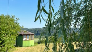 Un petit bâtiment vert, doté d’un toit en pente, entouré d’herbe et d’arbres.