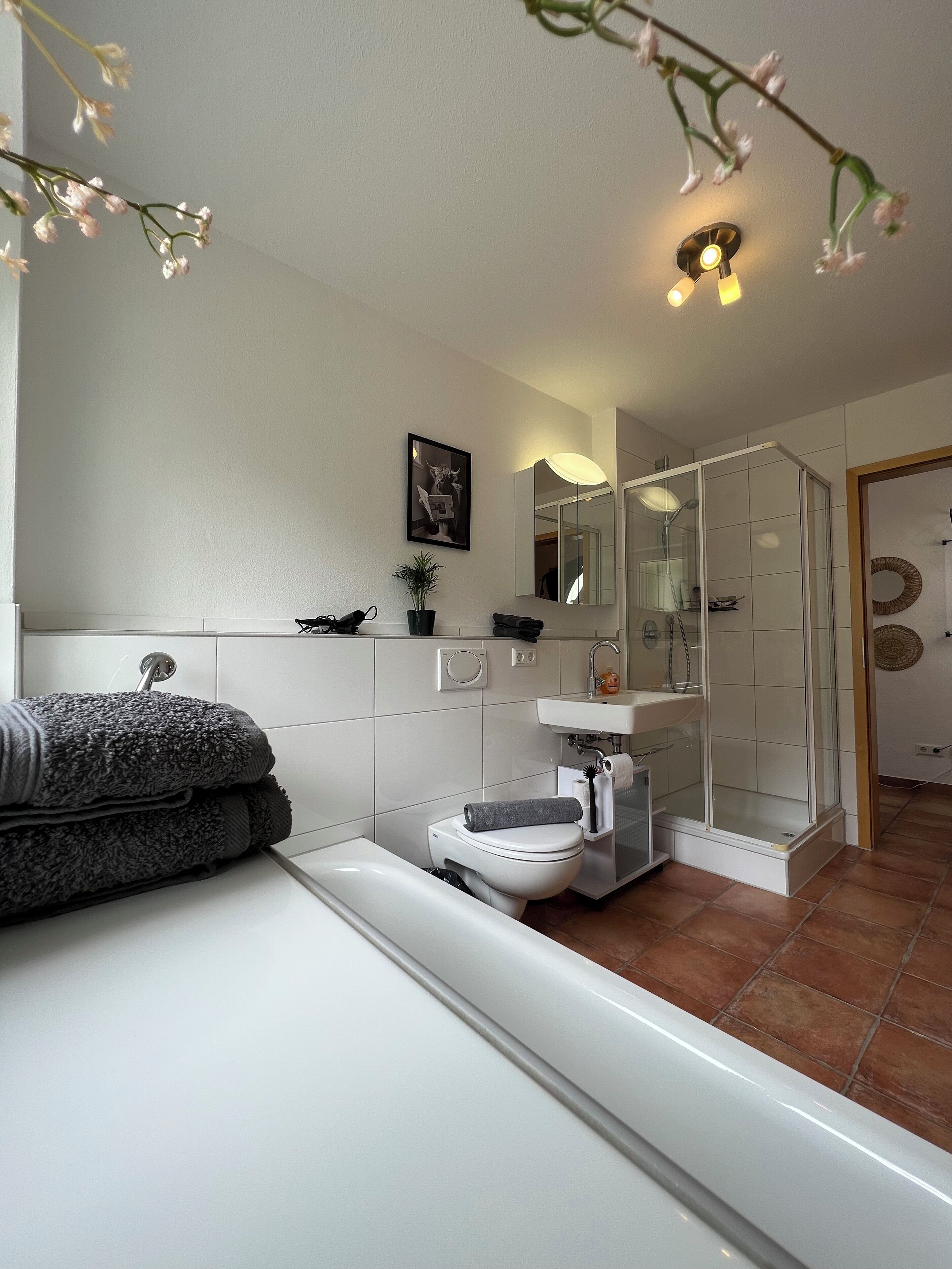 A modern bathroom with a bathtub, toilet, and glass-enclosed shower.