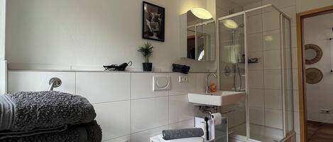 A modern bathroom with a bathtub, toilet, and glass-enclosed shower.