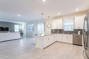 Enjoy cooking in this well-equipped kitchen with a central island, white cabinetry, and stainless steel appliances.