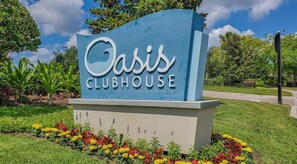 Welcome to the Oasis Clubhouse at ChampionsGate, featuring a beautifully maintained outdoor space with lush greenery and vibrant flowers.