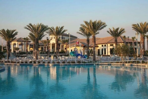 Relax by the resort's large pool surrounded by palm trees and lounge chairs.