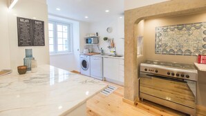 Una cocina moderna con encimera de mármol, horno empotrado y lavadora.