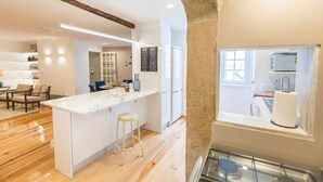 Una cocina moderna con una isla de mármol, piso de madera y vistas al área de comedor.