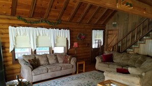 L’intérieur d’un chalet confortable, avec deux canapés, une petite table et un escalier.