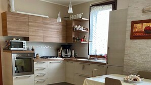 A modern kitchen with wooden cabinets, a microwave, a stove, and a dining area with a table and chairs.