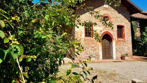 A rustic stone building with a brick facade, a wooden door, and a small arched window.
