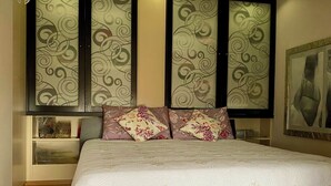 A bedroom with a bed, decorative pillows, a nightstand, and a painting on the wall.