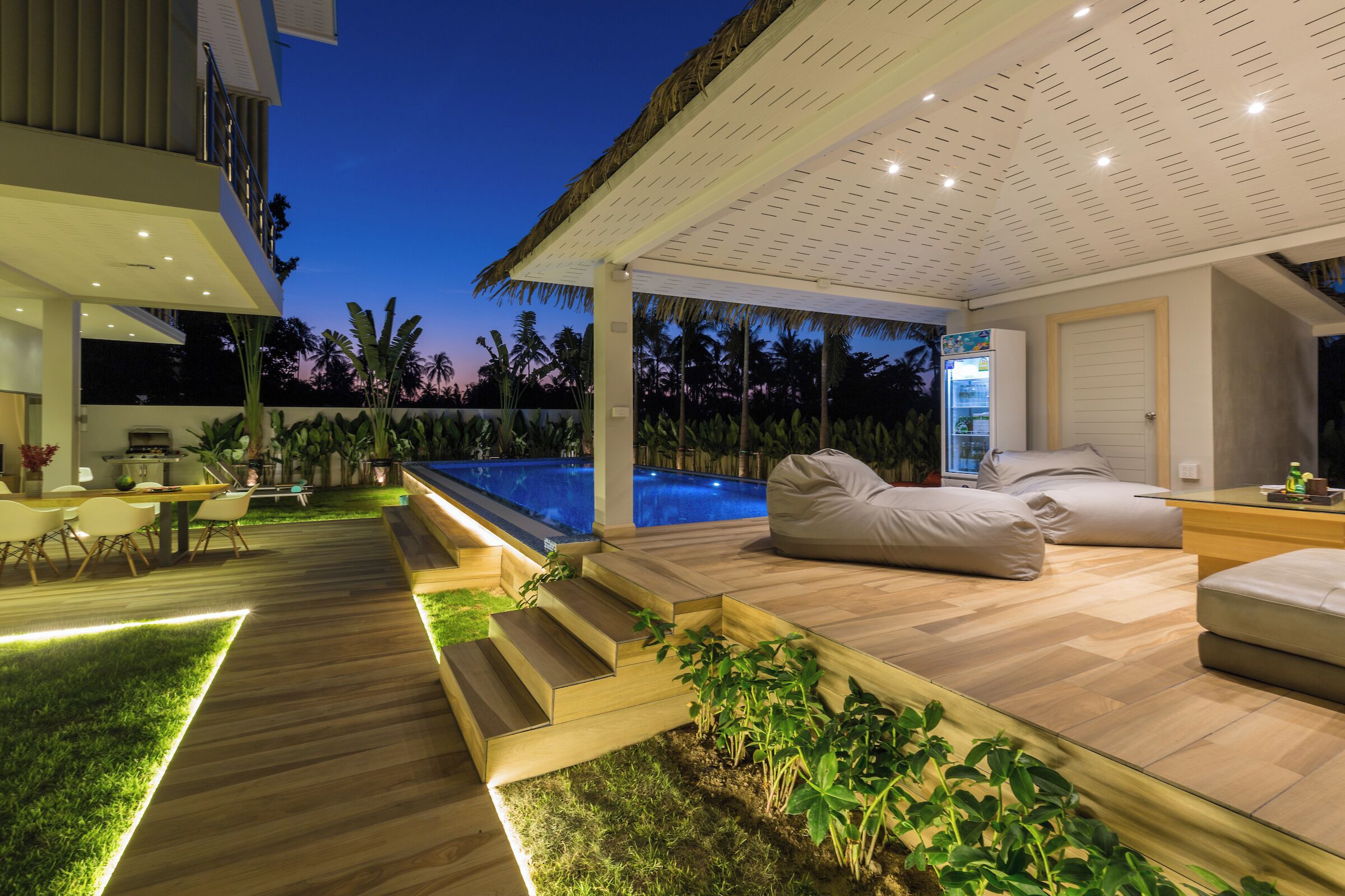 A modern outdoor living area with a pool, wooden deck, and seating.