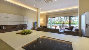 A modern kitchen with a central island, built-in cabinets, and a view to an outdoor seating area. - 5-bdr luxury villa at a villa resort (Koh Samui)