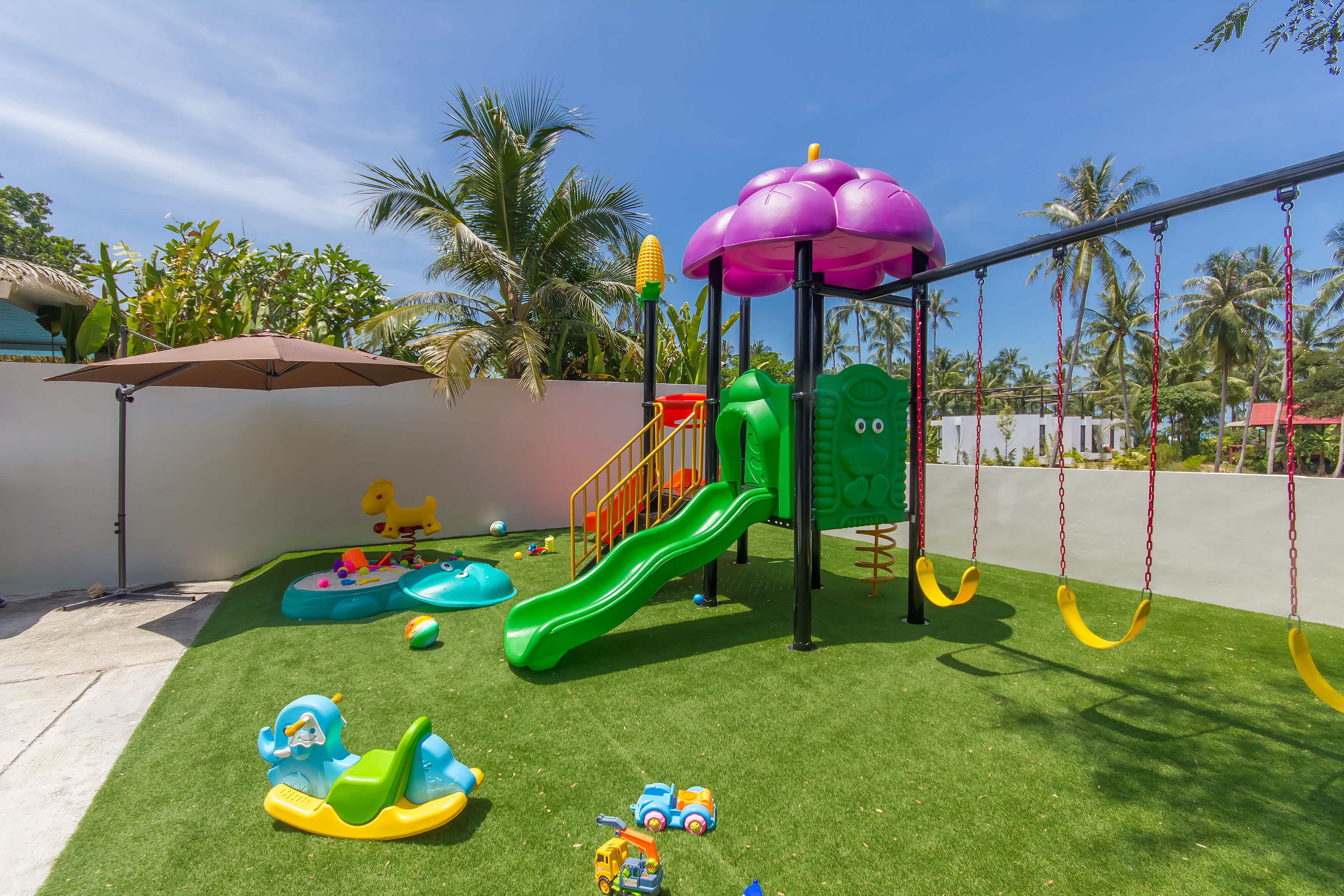 A children's playground with a slide, swings, and various play structures.