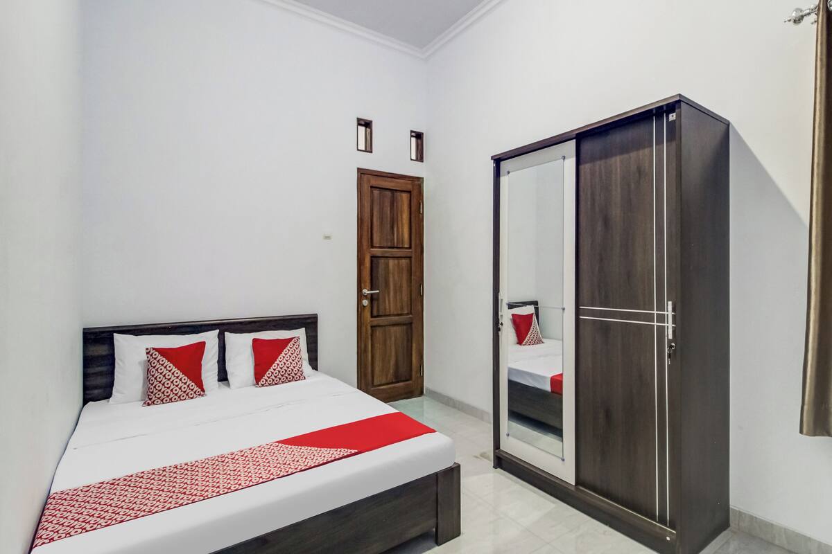 Un dormitorio con cama, armario, puerta y espejo.