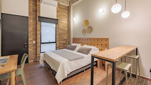 A modern bedroom with a bed, a wooden desk, and a chair. - The Somos Flats Laureles (Medellín)