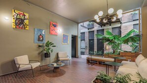 A modern lobby with a brick floor, white sofas, a coffee table, and artwork on the walls. - The Somos Flats Laureles (Medellín)