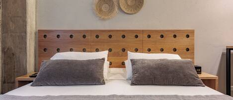 Una cama bien hecha con una colcha estampada, dos almohadas y un cabecero de madera con detalles circulares.