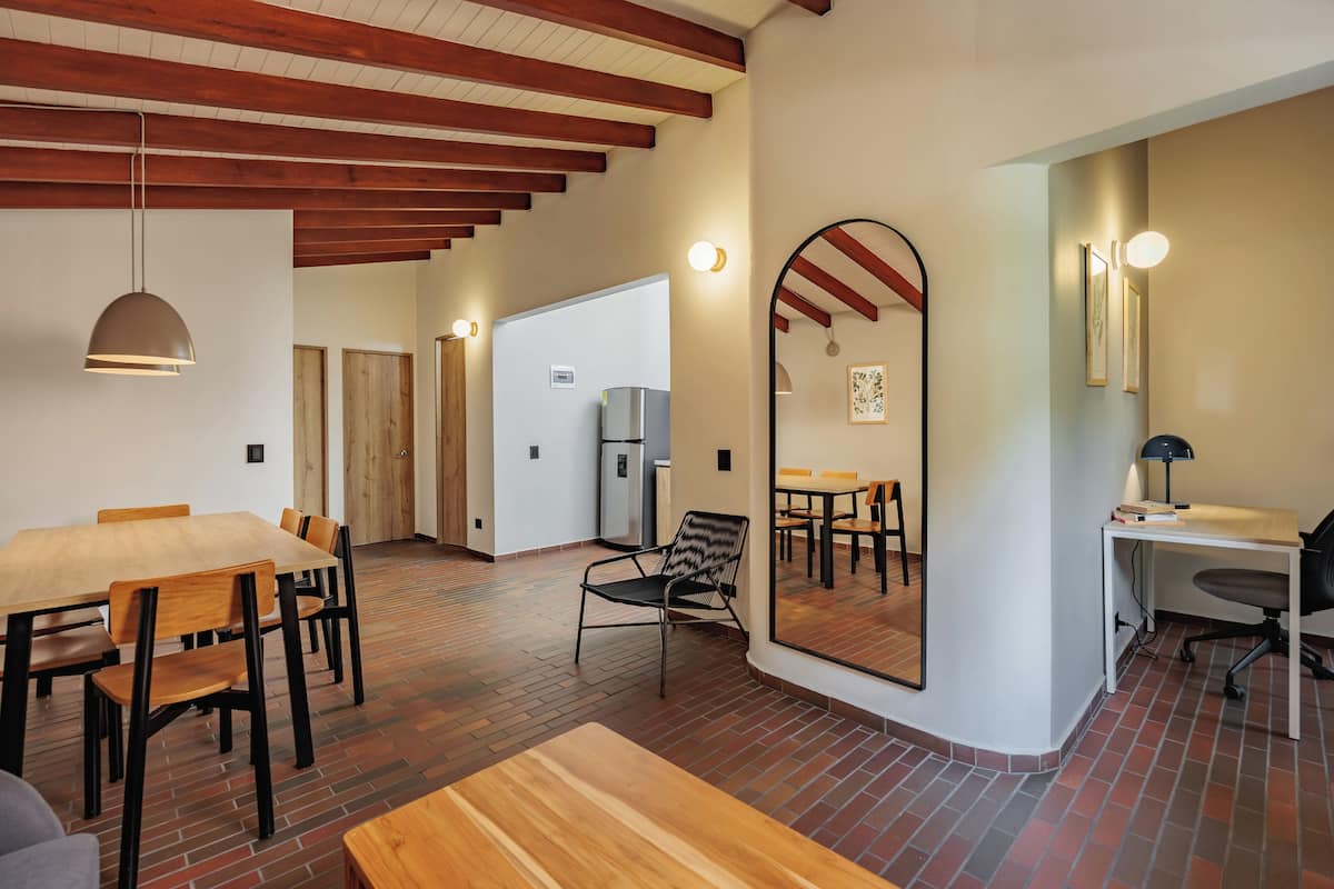 Um quarto amplo com uma mesa de jantar de madeira, cadeiras, um espelho grande e uma escrivaninha moderna.