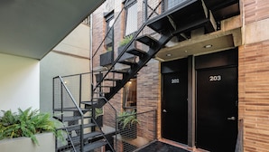 A building with a black metal staircase leading to a door marked 202. - The Somos Flats Laureles (Medellín)