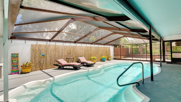 An indoor swimming pool with lounge chairs, potted plants, and a bamboo wall. - Winter Haven Retreat w/ Private Pool! (Winter Haven)