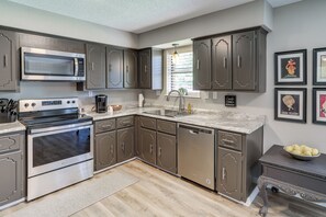 Una cocina moderna con electrodomésticos de acero inoxidable, armarios oscuros y una encimera de granito.
