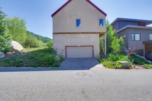 Ein zweistöckiges Haus mit Garage, umgeben von Grün und einer Hanglage.