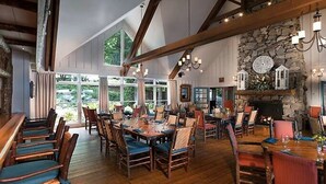 A spacious dining area with high ceilings, wooden beams, and large windows offering a view of the outdoors. - Two Bedroom at Trillium, NC 3575307 (Cashiers)