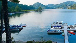 A calm lake with boats docked at a pier, surrounded by forested hills. - Two Bedroom at Trillium, NC 3575307 (Cashiers)