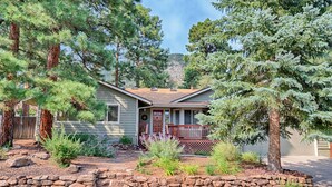 A house with a stone retaining wall, a wooden deck, and various plants. - Forest Heights (Flagstaff)