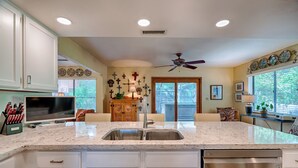 A kitchen with white cabinets, a granite countertop, a built-in dishwasher, and a ceiling fan. - Forest Heights (Flagstaff)
