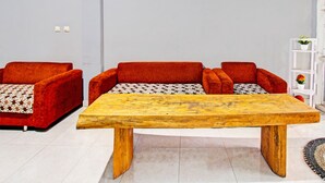 Un salon moderne avec une table basse en bois, des canapés rouges et une étagère blanche.