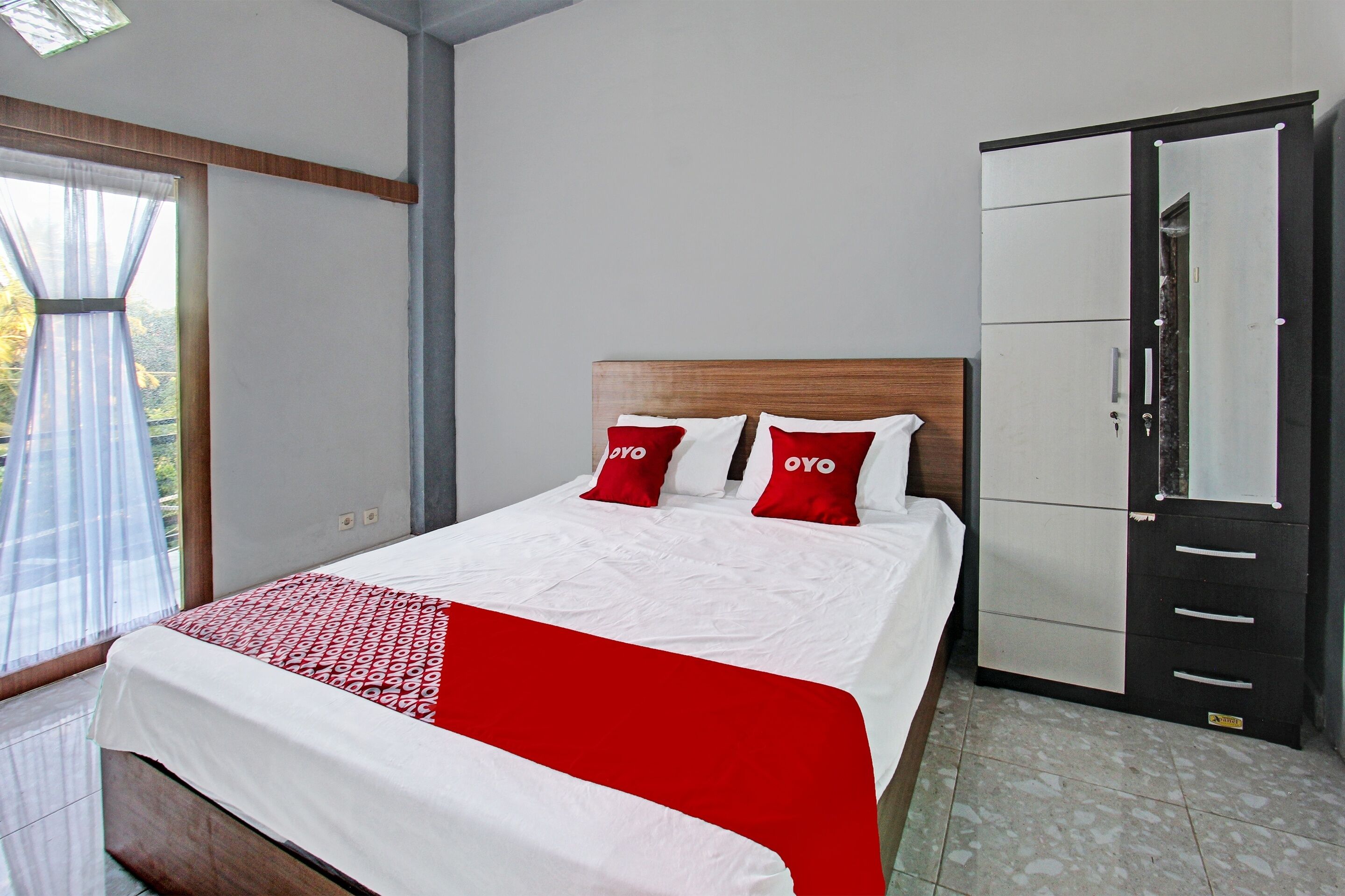 Een hotelkamer met een bed, een kledingkast en een raam met gordijnen.