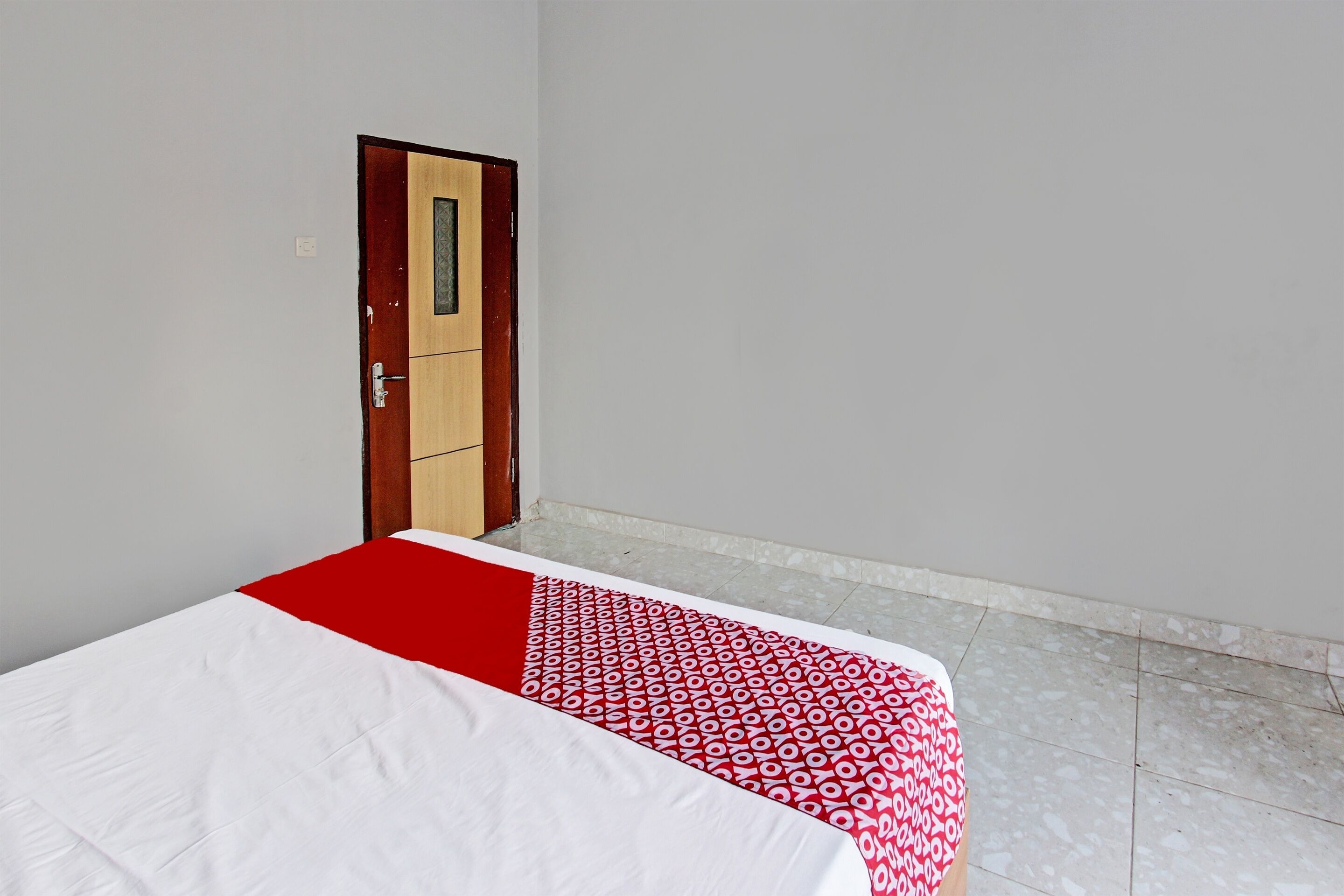 Une pièce avec un lit, une porte et un sol carrelé.