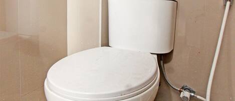 A toilet with a white tank and a floral-patterned floor.