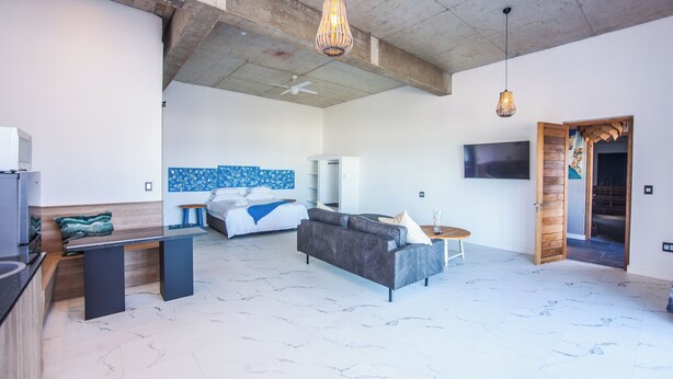 A modern living area with a sofa, a coffee table, a TV, and a kitchen area with a microwave.