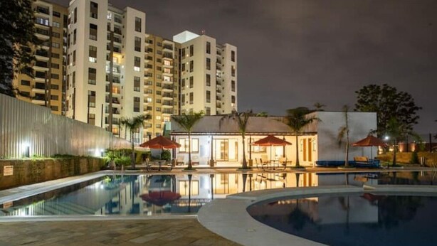 A swimming pool area with a building in the background. - Luxurious 2 Bed Garden City (Nairobi)
