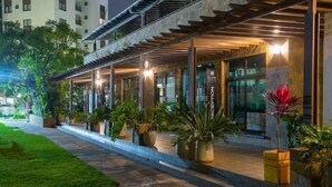 A hotel reception area with a modern design, featuring a covered walkway, potted plants, and a reception desk. - Luxurious 2 Bed Garden City (Nairobi)