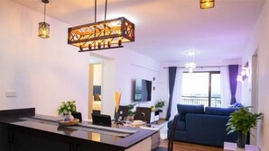 A modern living room with a sofa, a dining area with a table and chairs, and a kitchen area with a counter and cabinets. - Luxurious 2 Bed Garden City (Nairobi)