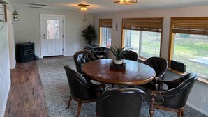 A dining area with a round wooden table, black leather chairs, and two wall-mounted lights. - HUGE house across st from GC railway- hot tub (Williams)
