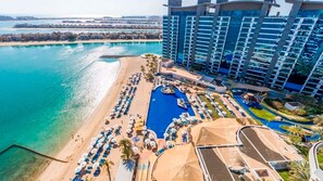 A resort with a large pool, beach area, and a high-rise building.