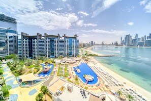 Ein Resort mit mehreren Hochhäusern, einem großen Poolbereich und einem Strand mit Sonnenschirmen.