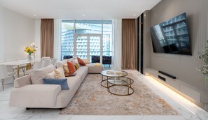 A modern living room with a large sofa, a coffee table, and a TV mounted on the wall.