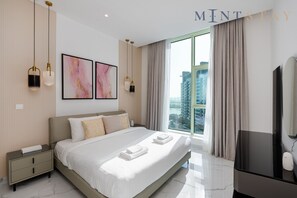 Ein modernes Hotelzimmer mit einem großen Bett, Nachttischen, einem Flachbildfernseher und Blick auf die Stadt.
