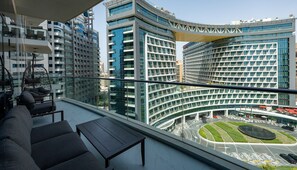 A modern building with a curved facade, a rooftop terrace with seating, and a view of the surrounding urban area.